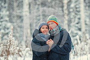 Portrait of a beautiful happy couples in winter forest. Husband and wife smiling.