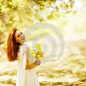 Portrait of beautiful happy ginger girl with yellow leaves in th