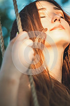 Portrait of beautiful happy girl swinging on rope swing outdoors,young woman enjoying nature, leisure activity, lifestyle concept