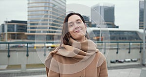 Portrait of beautiful happy healthy elegant business woman in beige coat looking at camera smiling in city background.