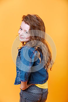 Portrait of beautiful happy little curly girl on orange background