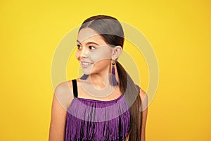 Portrait of beautiful happy smiling teenage girl on yellow studio background.