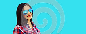 Portrait of beautiful happy smiling young brunette woman in sunglasses on blue background