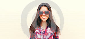 Portrait of beautiful happy smiling young brunette woman in sunglasses on white background
