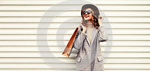 Portrait of beautiful happy smiling young woman with shopping bags looking up wearing checkered coat and round hat on white