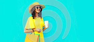 Portrait of beautiful happy smiling young woman with shopping bags wearing summer straw round hat on blue background