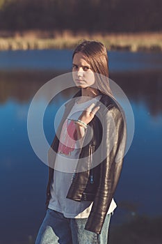 Portrait of a beautiful happy teenage girl in leather jacket outdoors in spring