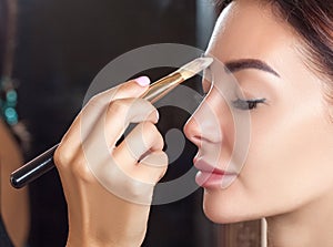 Portrait of a beautiful happy woman with clean skin in a beauty salon. Makeup artist does make-up to her. Professional makeup and