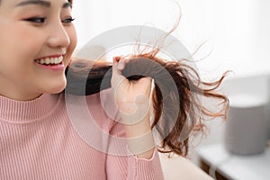 Portrait of beautiful happy woman drying her long hair with dryer