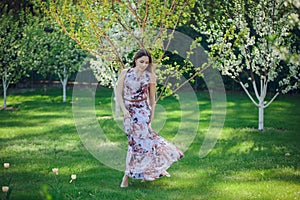 Portrait beautiful happy woman enjoying smell in a flowering spring blooming garden. Bright and fashionable smiling girl near blos