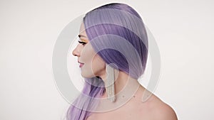 Portrait of beautiful happy woman in lilac wig and posing over light background. Closeup portrait of woman with colourful makeup i