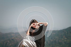 Portrait of a beautiful happy woman and smiling holding heart-shaped hands near the eyes showing love sign. over nature background