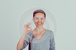 Portrait beautiful happy young woman showing Ok sign with hand isolated on light green gray wall background. Positive human