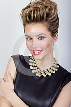 Portrait of a beautiful happy young woman smiling in a black evening dress with hair and make-up with expensive jewelry