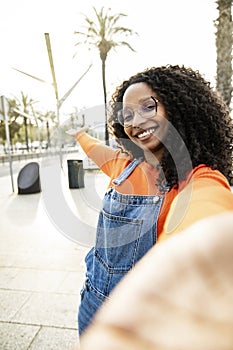Portrait of beautiful happy young woman smiling wearing glasses and a piercing looking at camera taking a selfie in the