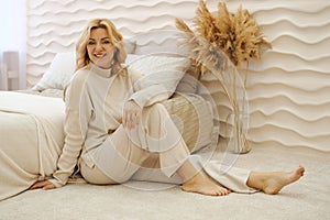 Portrait of a beautiful healthy adult woman who sits at home on the carpet near the bed. The concept of female beauty