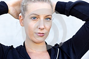 Portrait of beautiful, healthy, strong and fit young caucasian woman wearing a black hoodie flexing both arms muscles on