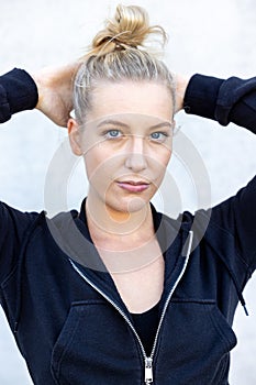 Portrait of beautiful, healthy, strong and fit young caucasian woman wearing a black hoodie flexing both arms muscles on