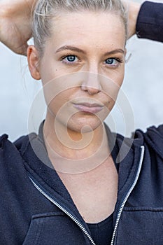 Portrait of beautiful, healthy, strong and fit young caucasian woman wearing a black hoodie flexing both arms muscles on