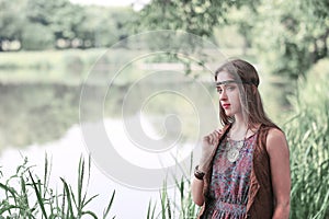 Beautiful hippie girl on the background of a forest lake