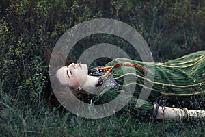 Portrait of beautiful hippie girl lying on the grass