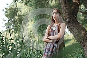 Beautiful hippie girl standing among trees in forest