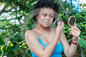 Portrait of beautiful Hispanic girl with makeup brush at the park