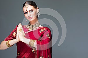 Portrait of a beautiful indian girl in a greetting pose to Namaste hands