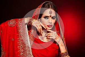 Portrait of beautiful indian girl in red bridal sari. Young hindu woman model with kundan jewelry set. Traditional Indian costume