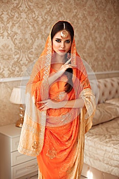 Portrait of beautiful indian girl in traditional saree in luxury interior. Young hindu woman model with kundan golden jewelry set