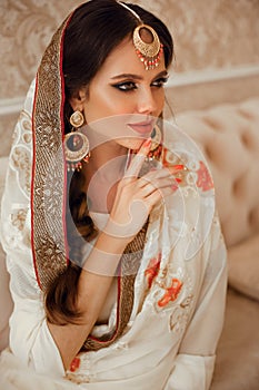Portrait of beautiful indian girl in traditional saree in luxury interior. Young hindu woman model with kundan golden jewelry set