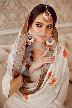 Portrait of beautiful indian girl in traditional saree in luxury interior. Young hindu woman model with kundan golden jewelry set