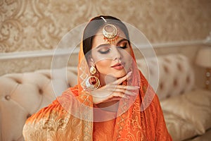 Portrait of beautiful indian girl in traditional saree in luxury interior. Young hindu woman model with kundan golden jewelry set