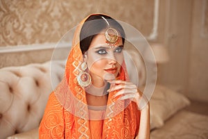 Portrait of beautiful indian girl in traditional saree in luxury interior. Young hindu woman model with kundan golden jewelry set