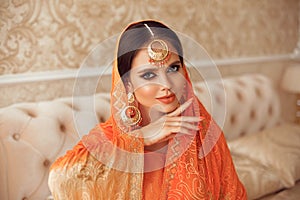 Portrait of beautiful indian girl in traditional saree in luxury interior. Young hindu woman model with kundan golden jewelry set