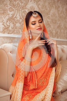 Portrait of beautiful indian girl in traditional saree in luxury interior. Young hindu woman model with kundan golden jewelry set