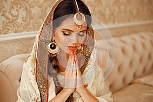 Portrait of beautiful indian girl in traditional saree in luxury interior. Young hindu woman model with kundan golden jewelry set