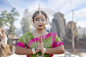 Portrait of a beautiful indian odissi dancer in a greetting pose to Namaste hands. India woman in traditional sari dress and jewel