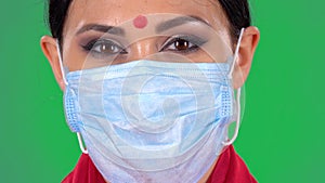 Portrait of beautiful indian woman in medical mask looking at camera. Close up of a brunettes face with bright eye