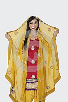 Portrait of beautiful Indian woman in salwar kameez standing over gray background photo