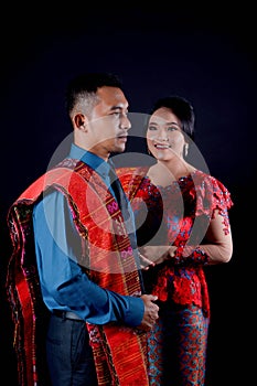 Portrait of beautiful indonesian couple wearing traditional batak costume isolated on black background