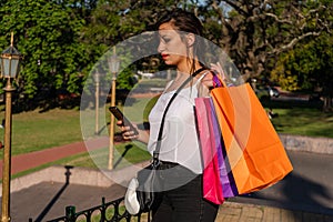 Portrait of a beautiful Latin woman answering a text message with her cell phone. Technology, shopping concept