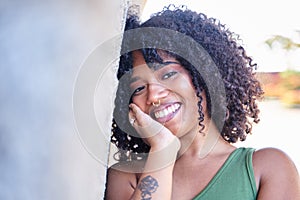 Portrait of beautiful latina woman. Smiling dreamy beautiful latina girl with black curly hair outside in the city