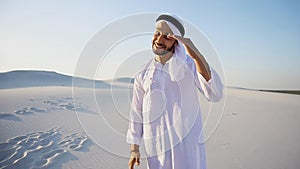 Portrait of beautiful laughing emirate male in sandy desert agai