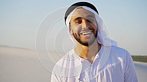 Portrait of beautiful laughing emirate male in sandy desert agai