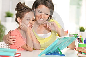 Portrait of a beautiful little cute girl reading book with mother
