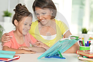 Portrait of a beautiful little cute girl reading book with mother