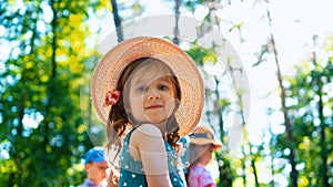 Portrait of a beautiful little girl in a hat. A cute girl is walking in the park with kids on vacation on a sunny day. Happy