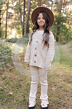 Portrait of beautiful little girl in hat looking at camera and smiling. Happy cute child having fun in park outdoors