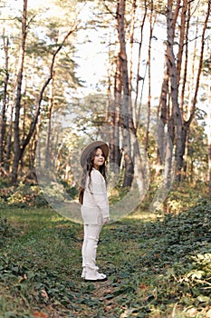 Portrait of beautiful little girl in hat looking at camera and smiling. Happy cute child having fun in park outdoors